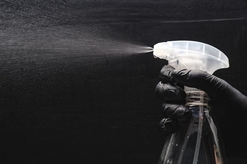 Janitor using mould cleaner in a school to ensure removal of mould.