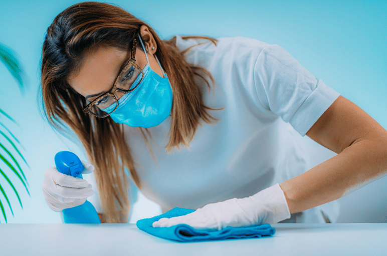 Woman cleaning a table surface with cleaning supplies