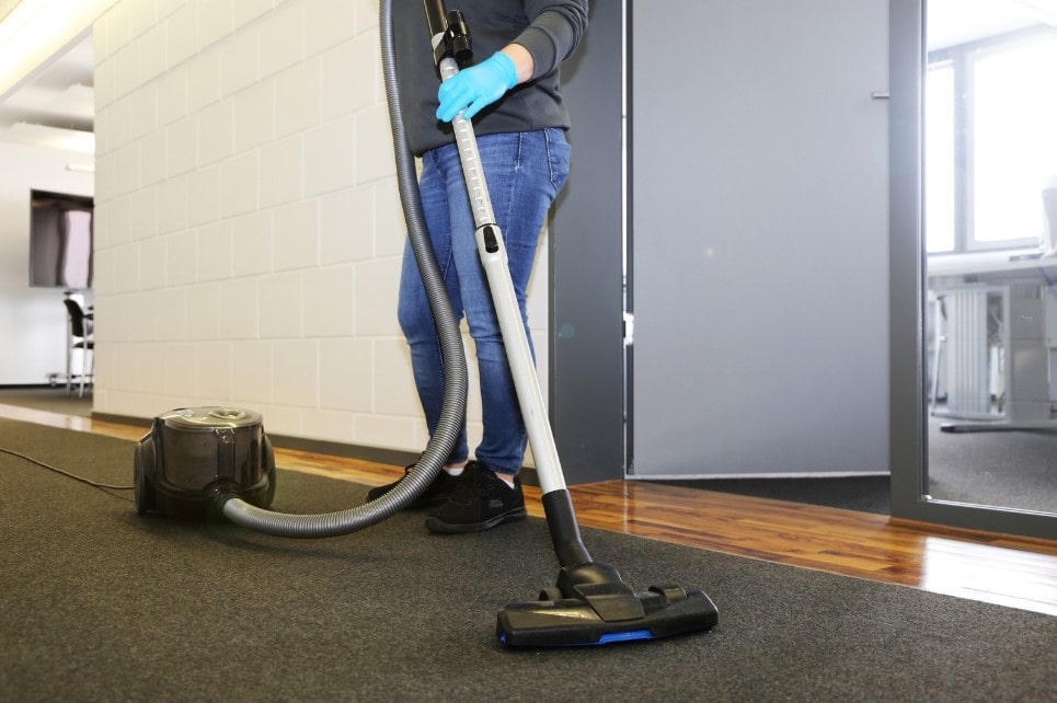 A man cleaning office floor with vacuum for overall cleanliness and health